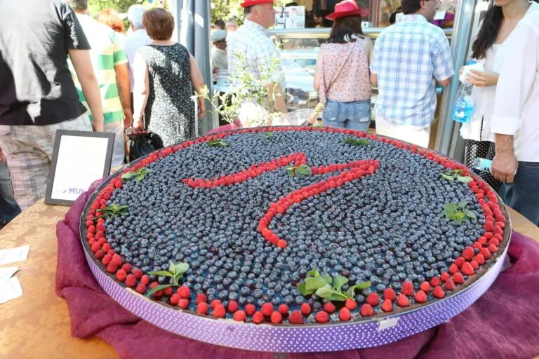 Grande tarte coberta de mirtilos e framboesas exposta numa banca da Feira Nacional do Mirtilo