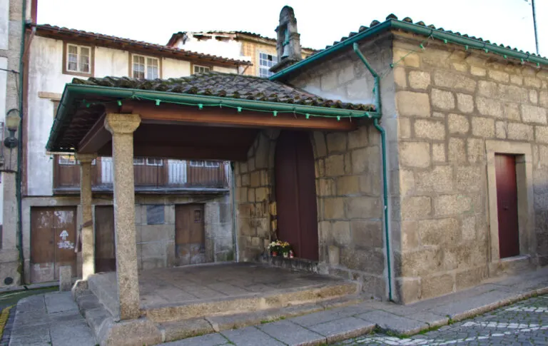 Alpendre da Capela de Santa Luzia, em Guimarães, com flores e velas junto à porta