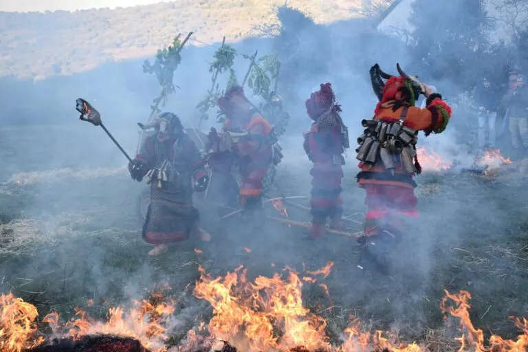 Grupo de caretos de Ousilhão entre o fumo e as chamas da palha queimada no campo