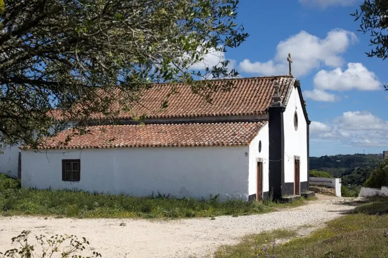 Ermida de Santo Antão, caiada de branco e com telhado de telha, entre oliveiras nos arredores de Óbidos