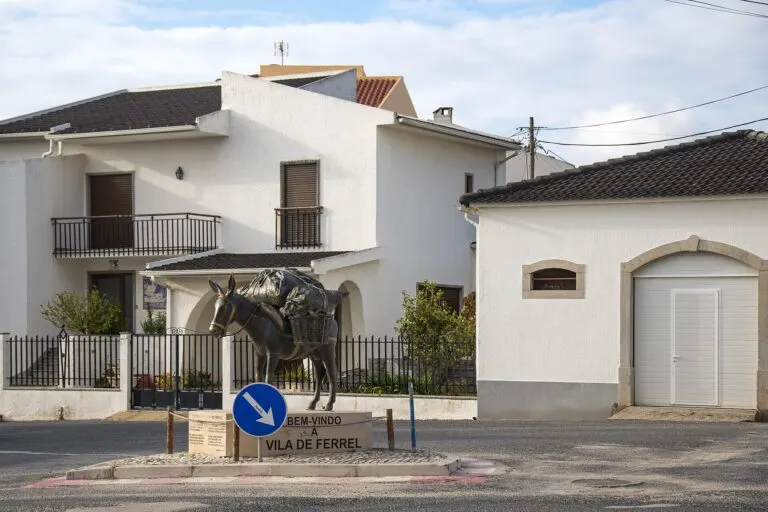 Estátua de um burro carregado na rotunda de entrada de Ferrel, com a inscrição «Bem-vindo à Vila de Ferrel»