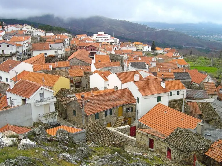 Telhados e casas de granito do centro de Folgosinho, com a serra coberta de nuvens por trás