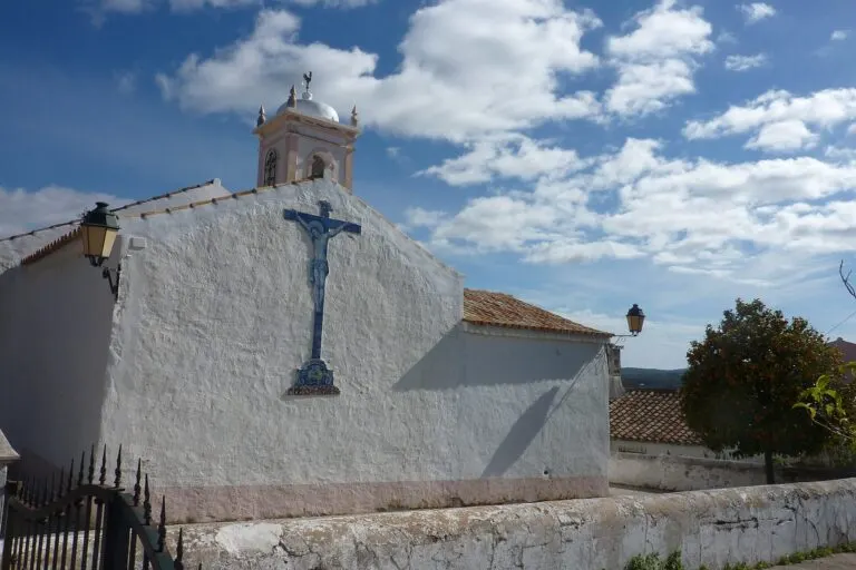 Crucifixo em azulejo azul e branco na parede caiada da Igreja de Benafim