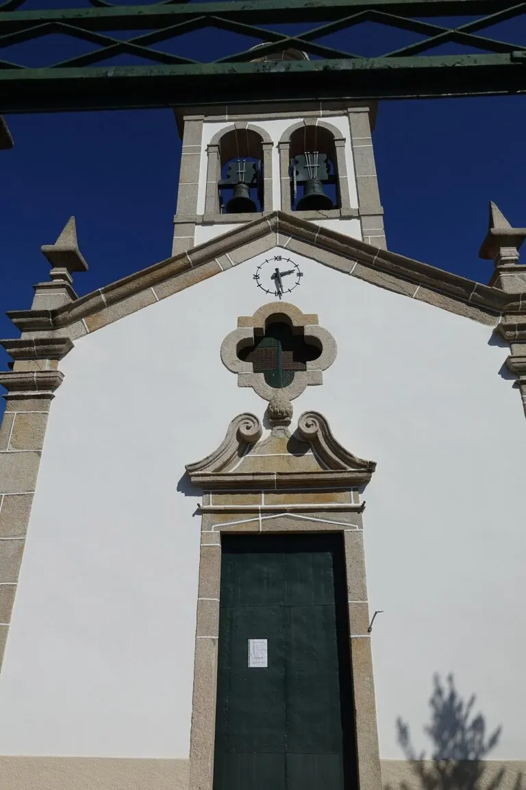 Fachada da igreja paroquial de Carvalhas, com os dois sinos, o relógio e a porta principal