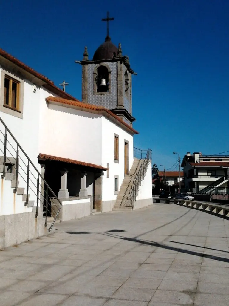 Lateral da igreja matriz de Olival, com paredes brancas, escadas exteriores e a torre sineira com cúpula