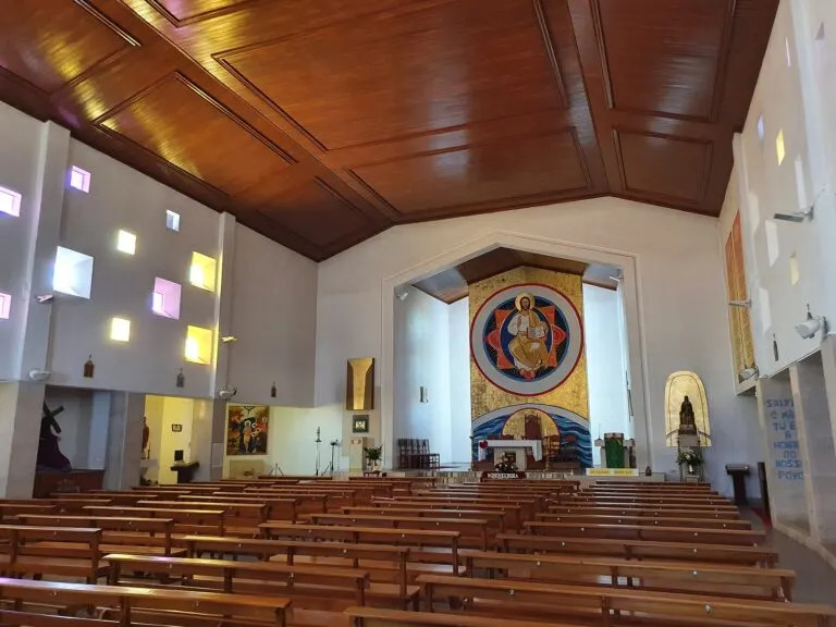 Interior da Igreja de Nossa Senhora de Monserrate, em Ribamar, com a nave de bancos de madeira e o mosaico do altar-mor