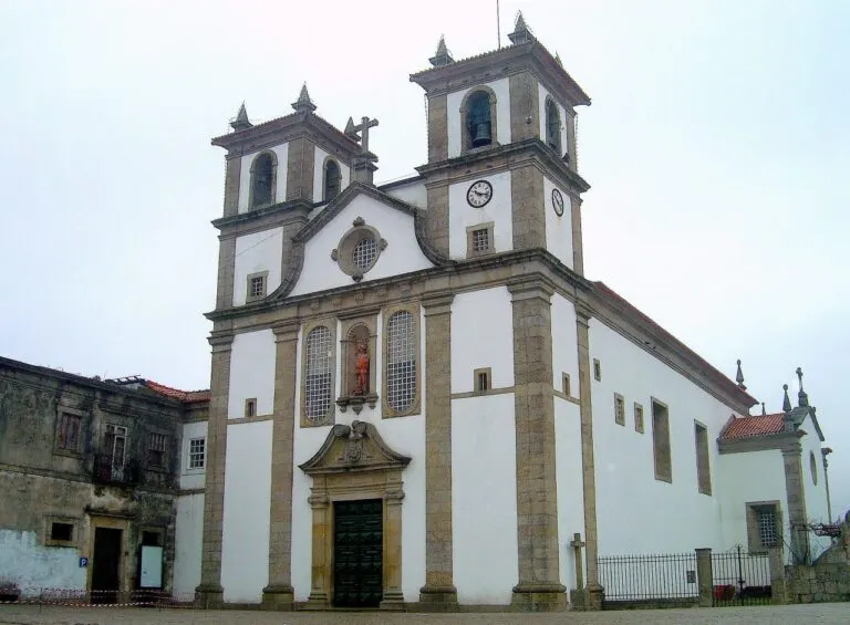 Fachada barroca da igreja do Mosteiro de Bustelo, com duas torres sineiras e a imagem de São Miguel no nicho