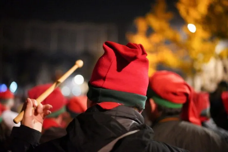 Nicolino de costas, com o barrete vermelho e verde, de baqueta erguida durante as Festas Nicolinas