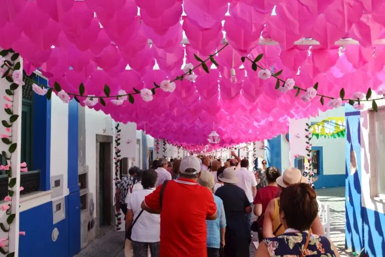 Visitantes numa rua coberta de flores de papel cor-de-rosa durante as Ruas Floridas de Redondo