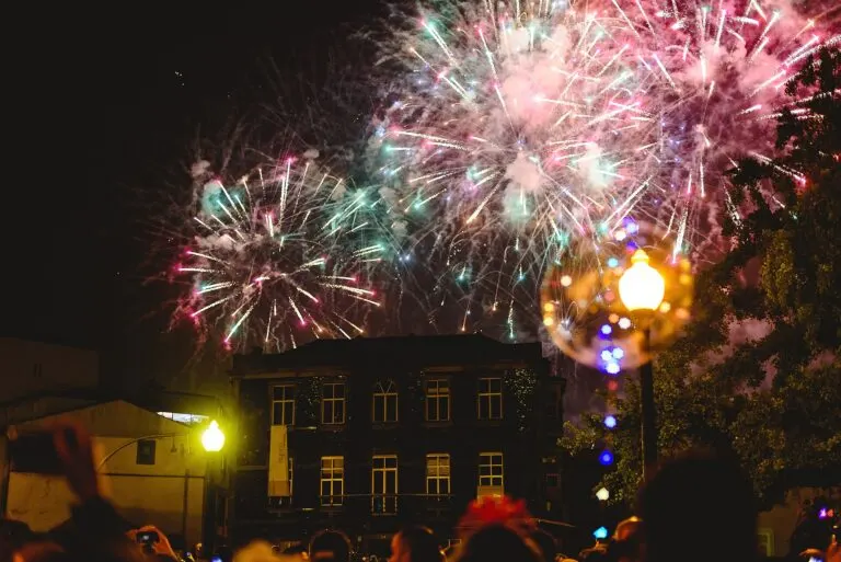Fogo de artifício da noite de São João sobre um edifício do Porto, com o público em contraluz