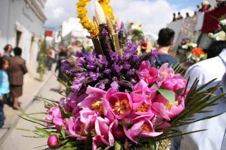 Tocha florida de peónias cor-de-rosa e flores roxas, erguida na procissão